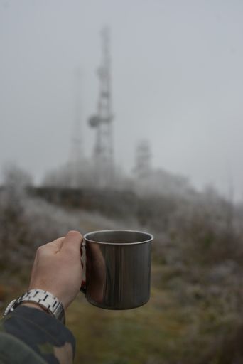A vertical shot of a cup with hot drink on frozen forest background