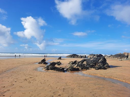 A beautiful shot of rocks on a beach under a cloudy blue sky