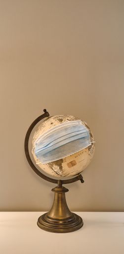 A vertical shot of a globe with a medical facemask on it -  coronavirus spread all over the world