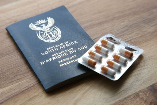 A high angle shot of a pack of capsules and a passport on a wooden surface