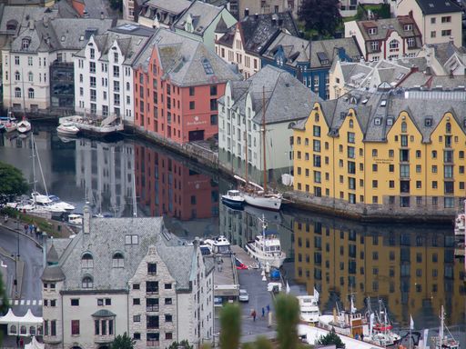An idyllic marina scene featuring buildings situated on the banks of a small river in Alesund, Norway, with colorful boats bobbing in the water