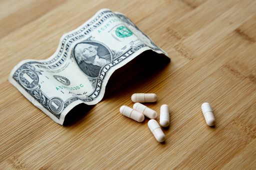 A high angle shot of some capsules and a dollar bill on a wooden surface
