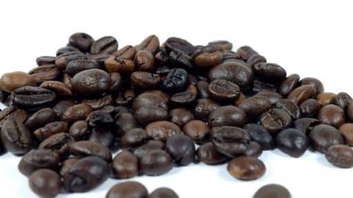 close up of roasted coffee beans on a white background