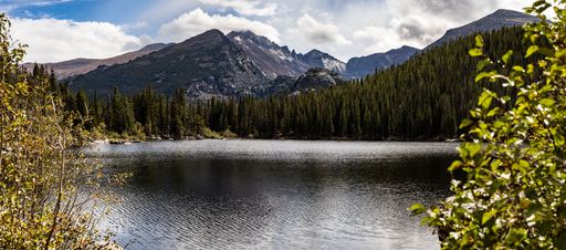 A landscape of shiny lake under forest and mountains in the background in the Park with cloudy sky