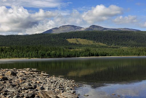 A lake surrounded by mountains against a blue cloudy sky in Are, Sweden