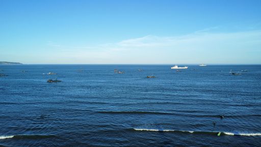 A drone view of the beautiful seascape with a ship and boats under a blue sky