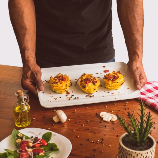 A close-up shot of a man serving pasta rolls on a tray