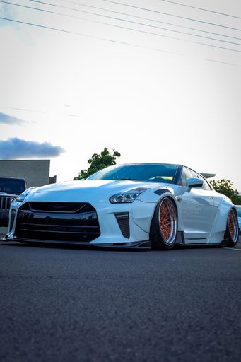 A vertical shot of a white tuned Nissan GTR found parked in the street