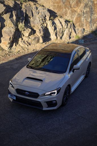 A vertical shot of a Subaru WRX found parked on the street on a sunny day
