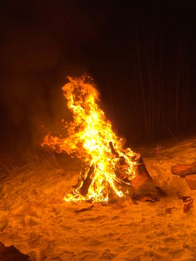 A vertical shot of a large burning bonfire on a beach camping site