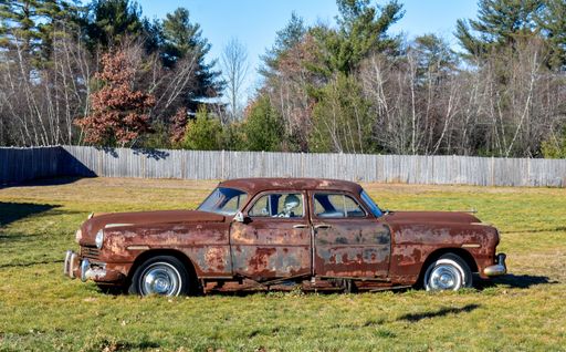 An old rustic retro car with two front sides on a green field