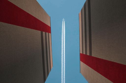 A low angle shot of a plane flying through the buildings