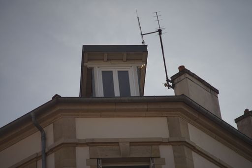 A low angle shot of an attic window against a blue sky on a sunny day