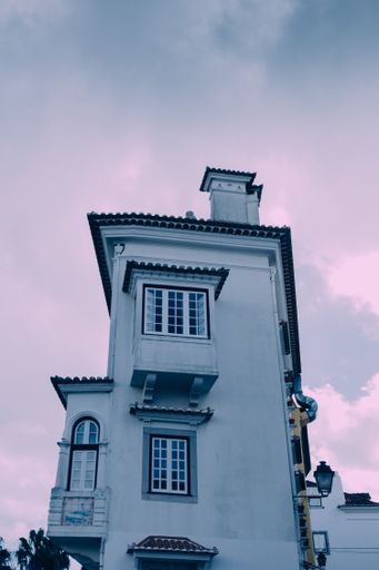 A low angle shot of a white building under a cloudy sky during sunset in Cascais, Portugal