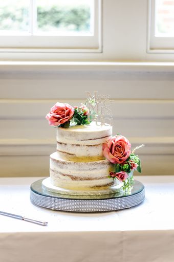 A vertical closeup of a wedding cake decorated with flowers on a table