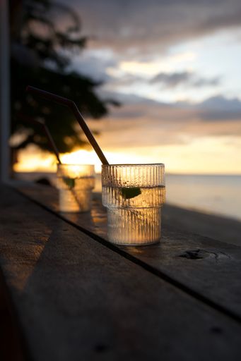 A selective focus shot of two cocktails on wooden bench