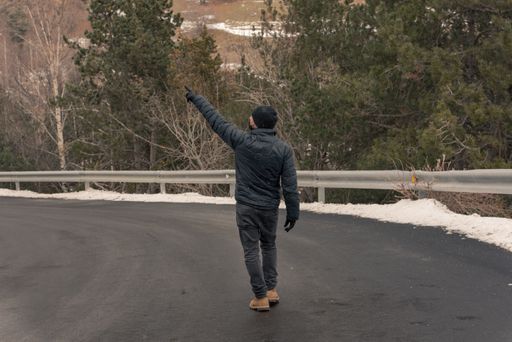 The man with black outfit walking along the empty snowy road in winter