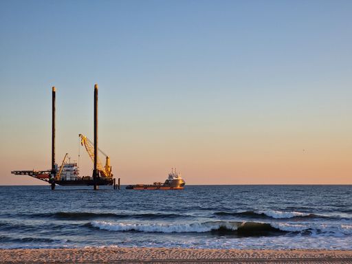 A lift boat and supply vessel setting up for an offshore wind farm at sunset in the USA.