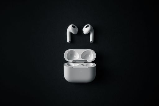 A top view of white wireless earbuds with case on a black background