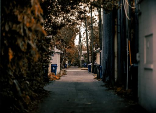 A narrow road in the urban area with recycle bins on the street
