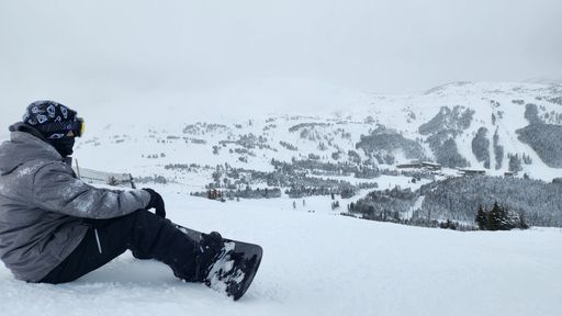 A guy sitting on the snowy mountain while skiing in Sunshine Village Ski resort in Canada