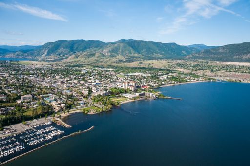 An aerial shot of the Okanagan Lake with Penticton city on the shore and hills in the background