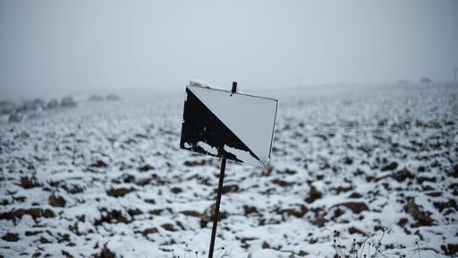 A closeup shot of a black and white post in the winter field