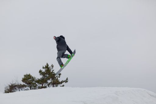 A snowboarder jumping high through the air at the Wisp Ski Resort in Deep Creek Lake Maryland