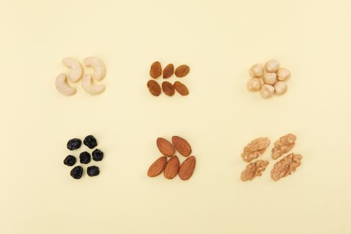 A high angle shot of groups of different nuts and seeds on a yellow surface