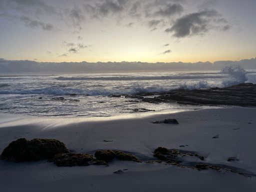 A beautiful sandy beach with splashing waves of the sea in the background at sunset