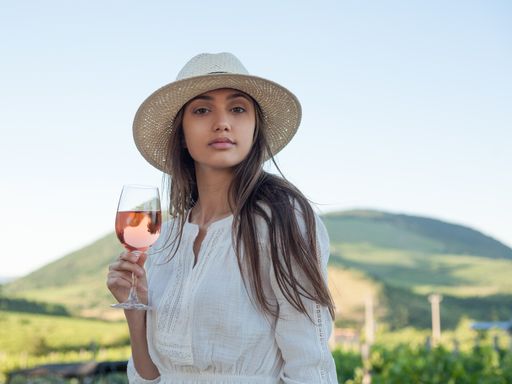 Portrait of beautiful brunette woman having wine outdoors in the vineyards.
