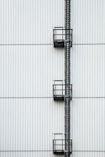 A vertical shot of a tall white building with a ladder on the side