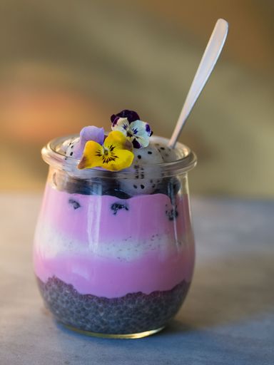 A vertical closeup shot of a healthy drink with different fruits of wild berries and chia seeds