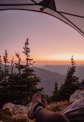 A vertical shot of highlands in North cascades national park at the sunset, camper's legs in Washington US