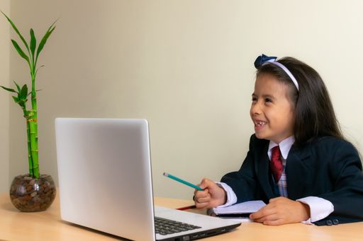 A beautiful Colombian girl wearing a school uniform doing homework on her notebook