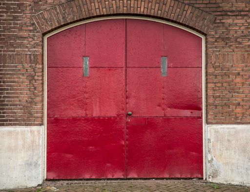 An arched type red metal door for a brick building