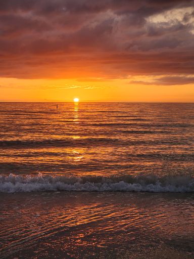 A vertical shot of a cloudy sunset sky over the sea