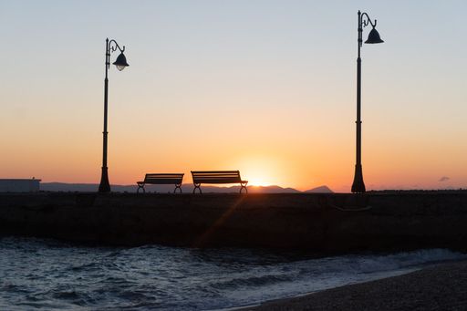 A tranquil scene of a lake at sunset, featuring two benches placed by the water's edge