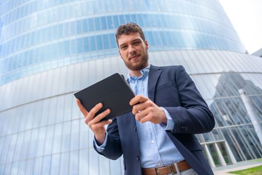 A handsome young businessman with tablet outside the office in a business park