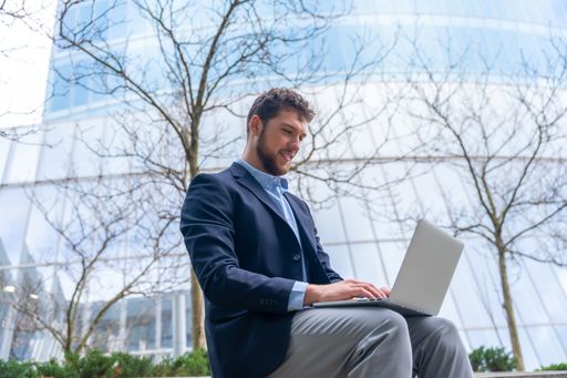 A handsome young businessman working on computer outside the office in a business park