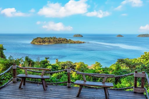 Two wooden benches facing the ocean with a picturesque Koh Chang island in Thailand