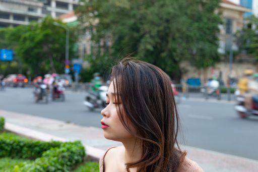 A shallow focus shot of an Asian female posing at the camera with motorcycles in the background