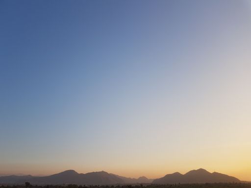 An expansive blue sky providing a backdrop to a mountain range on the horizon