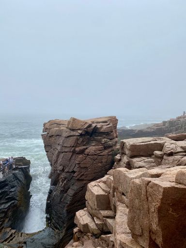 A vertical shot of huge rock formations with the clean sea in the background during daytime