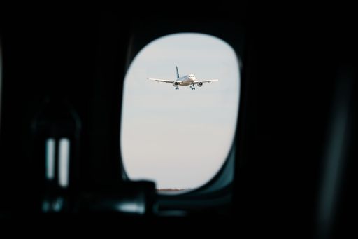A beautiful shot of an airplane flying near an airport visible through an airplane window
