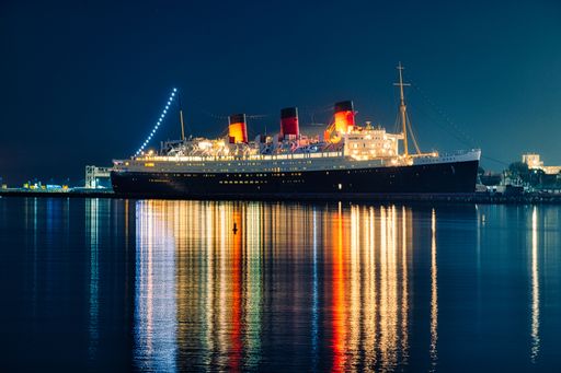 A stunning view of a cruise ship sailing on the water against the backdrop of a city skyline, illuminated at night by sparkling lights