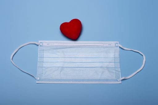 A sanitary mask and a small red heart decoration - Valentine's Day during the pandemic