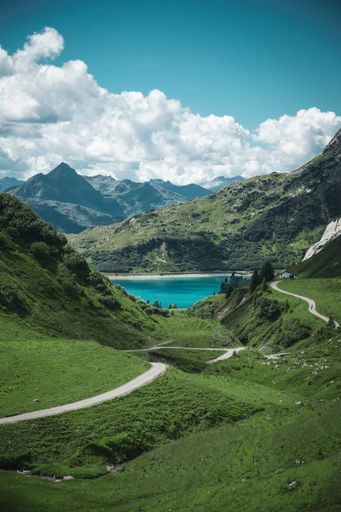 A vertical shot of a mountain lake surrounded by lush greenery and green trees