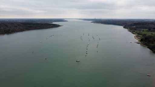 A drone shot of boats on the river surface under the cloudy sky
