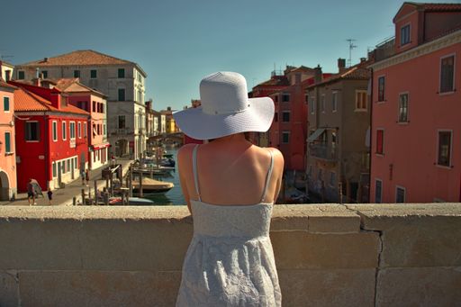 A female from behind with gondolas in Grand Canal between the buildings in Venice, Italy